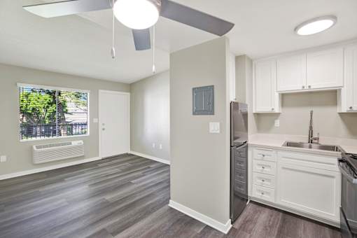 A kitchen with white cabinets and a grey fridge.