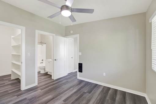 A room with a ceiling fan and a grey floor.