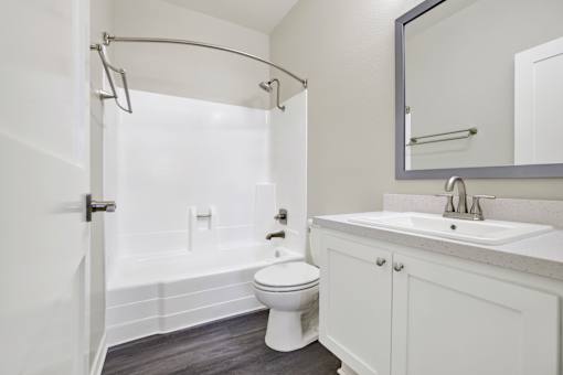 A white bathroom with a toilet, sink, and shower.
