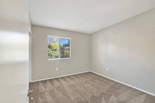 A room with a window and carpeted floor.