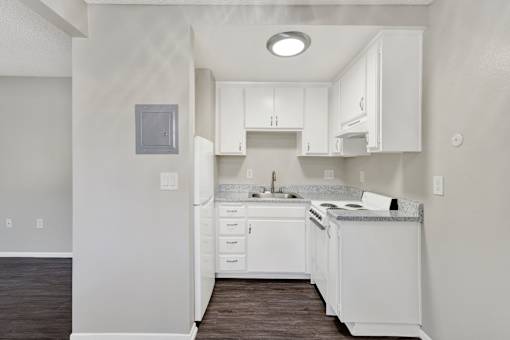 A white kitchen with a sink and a refrigerator.