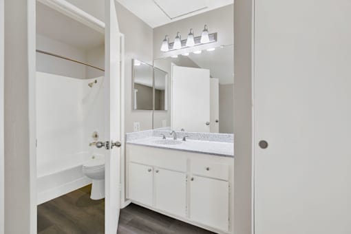 A white bathroom with a toilet, sink, and mirror.