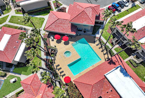 A red roofed house with a swimming pool in the backyard.