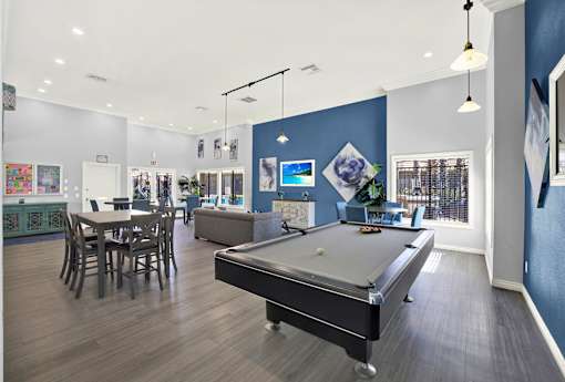 A billiard table is in the middle of a room with a dining table and chairs.