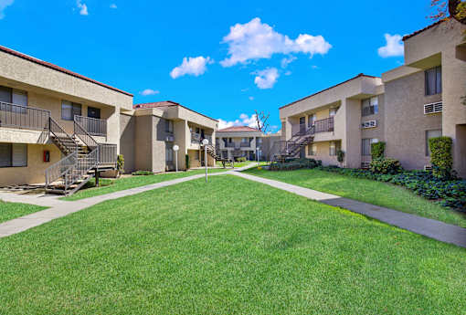 A sunny day at the apartment complex with green lawns and buildings on either side.