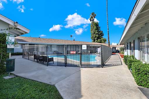 A pool surrounded by a black fence with a sign on the left.