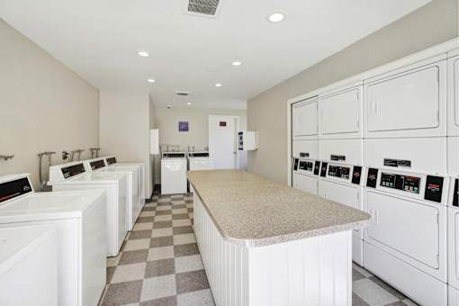 Community laundry facility with folding table at ELEVATE Apartments HOMES, Placentia