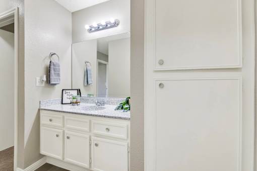 Bathroom vanity with white cabinetry and storage at ELEVATE Apartments HOMES, California