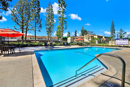 Swimming pool with patio seating and umbrellas at ELEVATE Apartments HOMES, Placentia, CA 92870