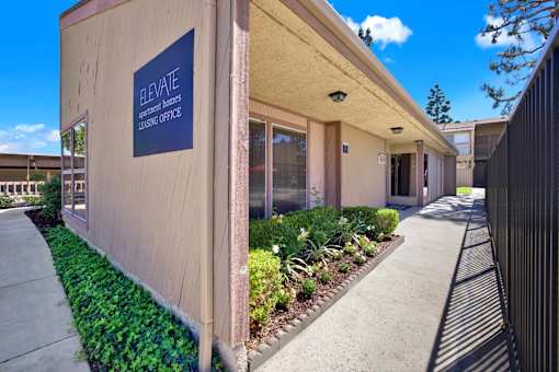 Leasing office entrance with signage and garden at ELEVATE Apartments HOMES, Placentia, 92870
