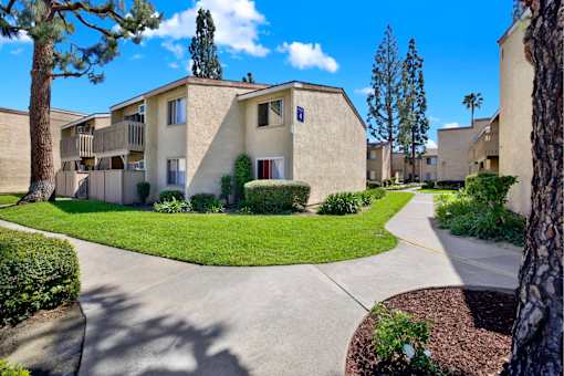 Apartment community pathway with green lawn at ELEVATE Apartments HOMES, Placentia, California