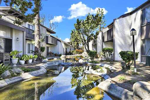 A serene courtyard with a pond and apartment buildings. at THE STREAMS Apartments, Fullerton, California