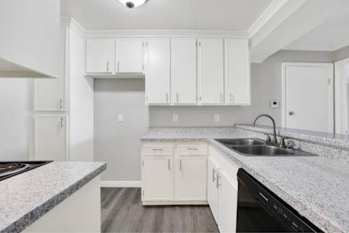 A kitchen with white cabinets and a granite countertop at THE STREAMS Apartments, Fullerton
