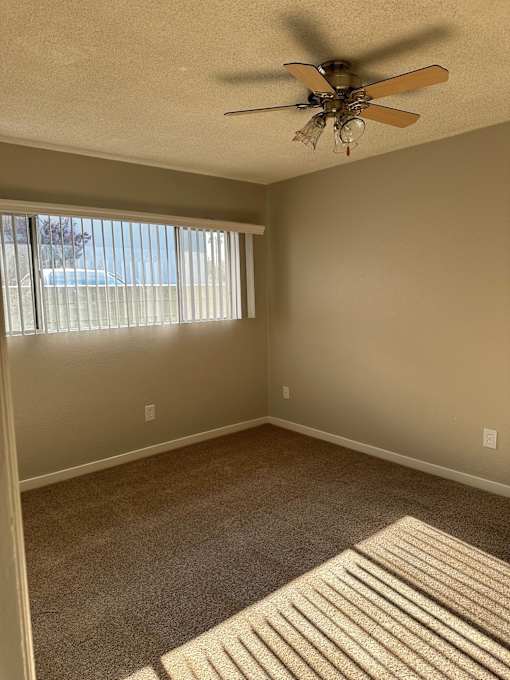an empty living room with a ceiling fan
