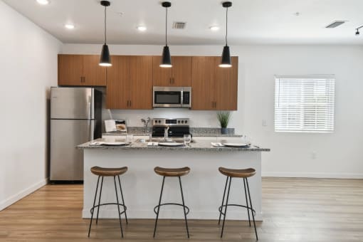 a kitchen with a island and three bar stools in front of a kitchen counter at Gibson Oaks, Lakeland, 33809