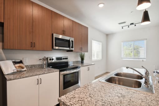 a modern kitchen with granite counter tops and stainless steel appliances at Gibson Oaks, Lakeland, 33809