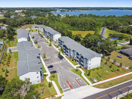 an aerial view of apartment buildings with a lake in the background at Gibson Oaks, Lakeland, 33809