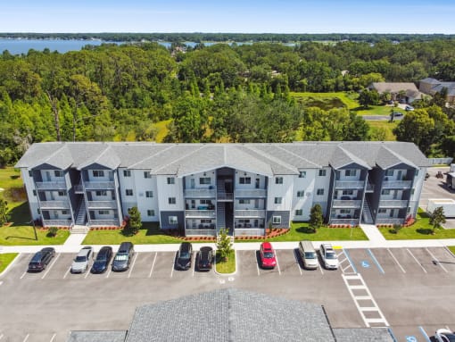 an aerial view of an apartment building and parking lot with cars at Gibson Oaks, Lakeland, 33809