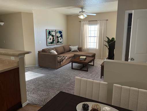 A living room with a brown couch and a painting on the wall.