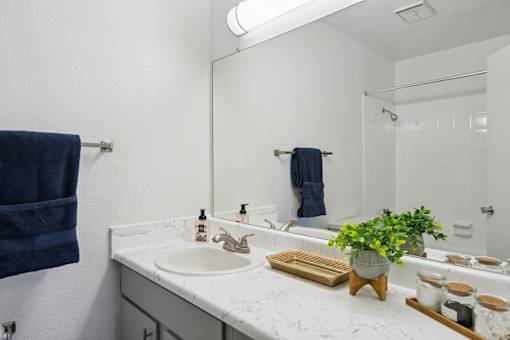 A bathroom with a white countertop and a blue towel hanging on the wall.