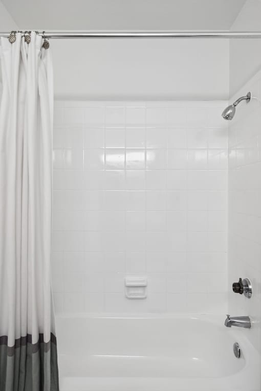 A white bathroom with a shower curtain and a white tub.