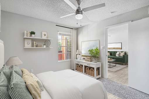 A bedroom with a bed, a ceiling fan, and a window.