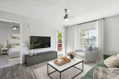 A modern living room with a flat screen TV, a sofa, a coffee table, and a bed.
