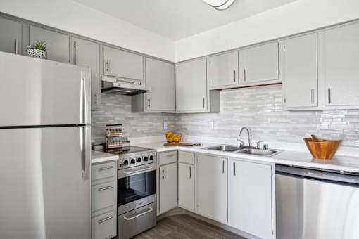 A modern kitchen with white cabinets and a stainless steel refrigerator.