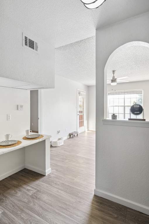 A white kitchen with a counter and a fan.