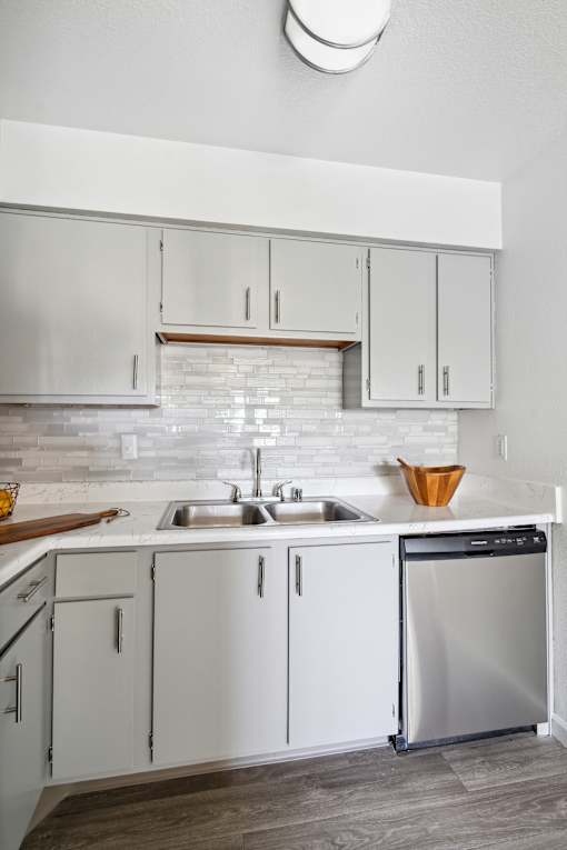 A modern kitchen with white cabinets and a stainless steel dishwasher.