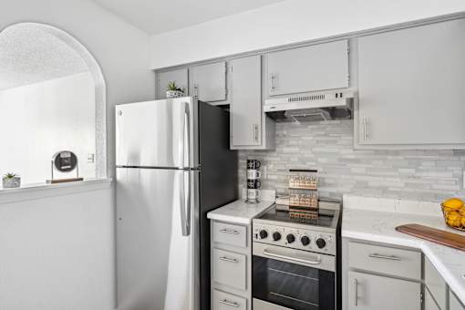 A white refrigerator stands next to a stove in a kitchen.