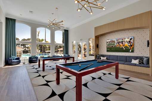 a billiards room with two pool tables and a tv in front of windows