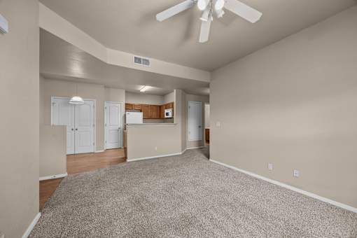 A spacious room with a ceiling fan and carpeted floor.