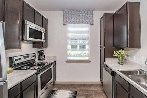 A kitchen with dark brown cabinets and stainless steel appliances.