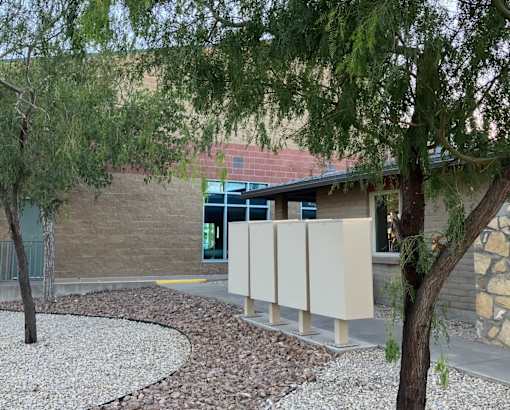 A building with a curved walkway and trees in front.