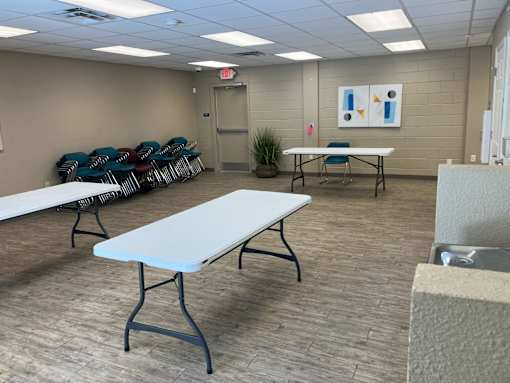 A room with tables and chairs and a painting on the wall.