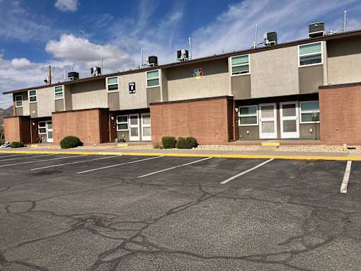 A parking lot in front of a building with a clear blue sky.