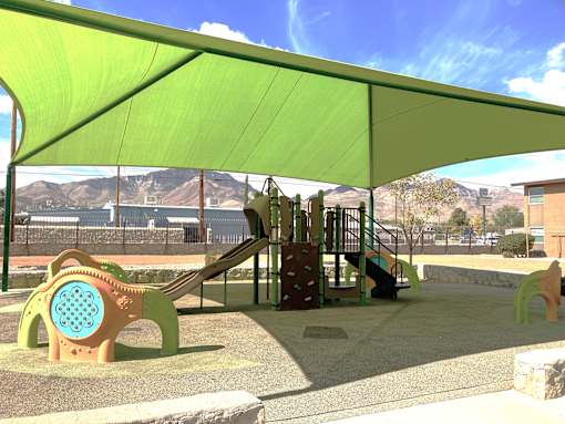 A playground with a green canopy and a slide.