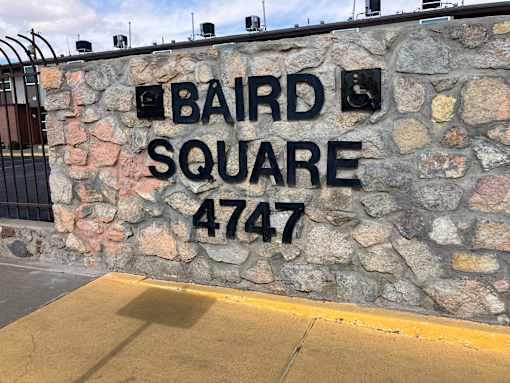 A stone wall with the words Baird Square 4747 on it.