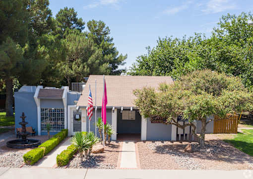 A house with a flag and a tree in front.