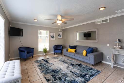 A living room with a grey couch, blue chairs, and a white ottoman.
