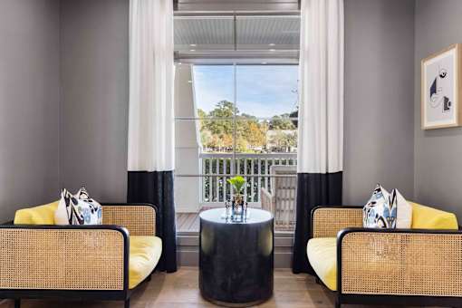 A living room with two yellow chairs and a round black table.