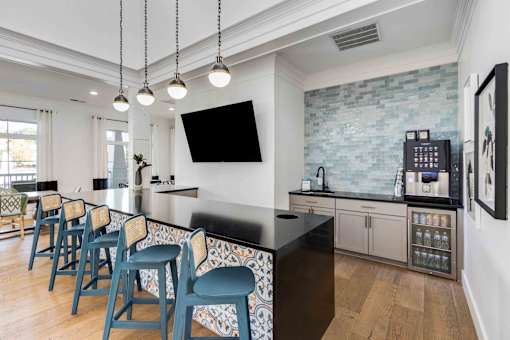 A kitchen with a black counter and blue chairs.