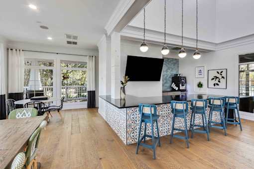 A kitchen with a bar and blue chairs.