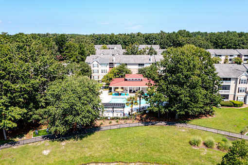 A large building with a red roof is surrounded by trees.