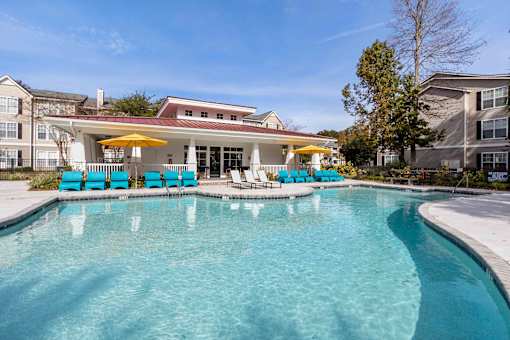 A swimming pool with blue chairs and a yellow umbrella.