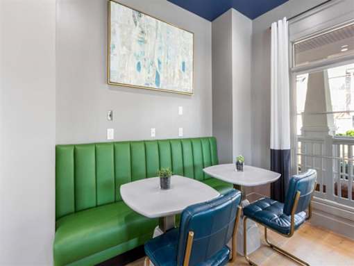 A white table with a green sofa and a painting on the wall.