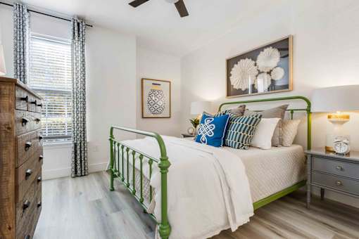 A bedroom with a green bed frame and a white bedspread.