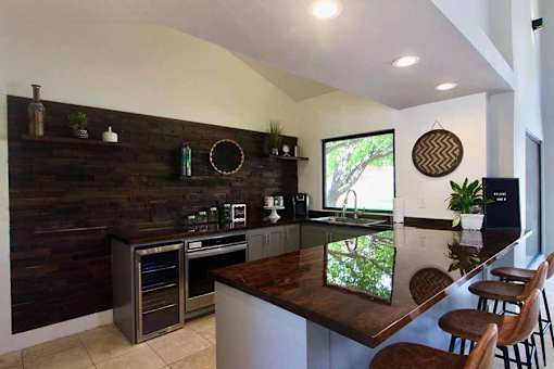 A kitchen with a wooden bar counter and stainless steel appliances.