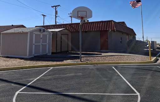 A basketball court with a basketball hoop and a portable building in the background.